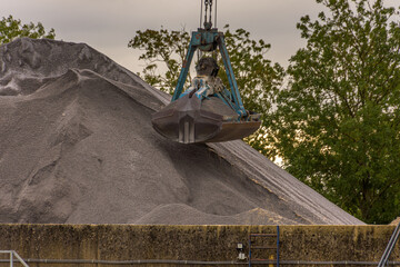 A big iron excavator collects graphite sand on the construction site