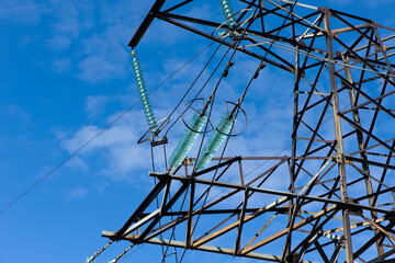 power line construction of cable supports and insulators. High voltage power line on blue sky background in Sunny day. Close-up. industry, iron construction, high voltage pole