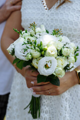 newlyweds hold a wedding bouquet with light light flowers