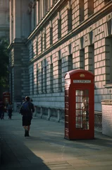 Poster Vertical shot of red phone booths on the sidewalks of the city © Adrien Dupart/Wirestock