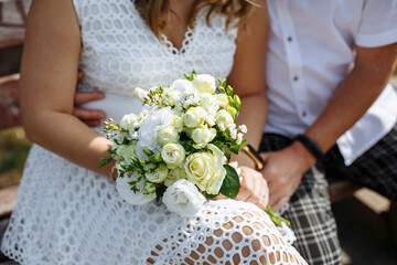 newlyweds hold a wedding bouquet with light light flowers