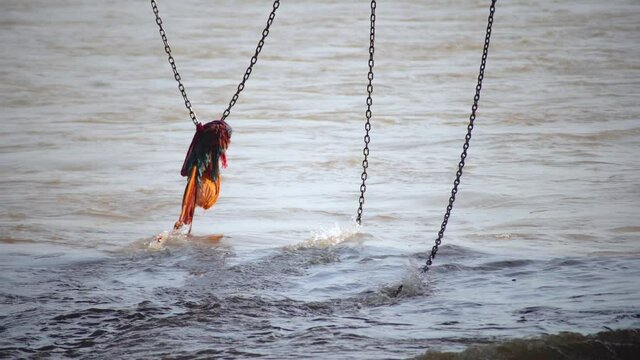 slow motion shot of colorful saffron orange cloth placed on a chain hanging into the ganga river at Haridwar to help people who fall in, placed as a mark of faith and decoration in this holy hindu