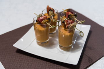 Quatre verrines de traiteur - Bisque et moule sur une assiette blanche