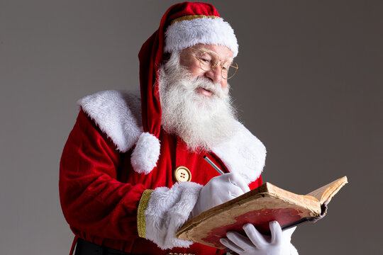 Santa Claus with a old red cover book. Jotting down names gifts for Christmas. Christmas is coming