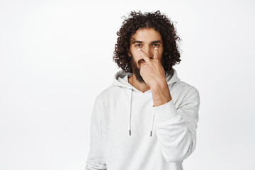 I am watching you. Serious guy making eye contact gesture, being suspicious, standing over white background