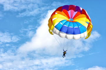 Paragliding using a parachute on background of blue cloudy sky. - obrazy, fototapety, plakaty