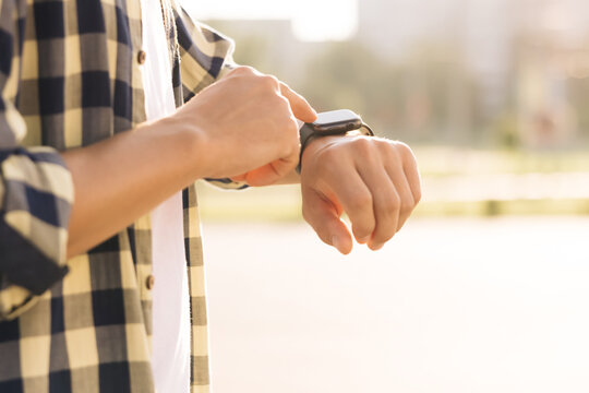 Smart watch. Smart watch on a man's hand outdoor. Man's hand touching a smart watch. Close - up shot of male's hand uses of wearable smart watch at outdoor.