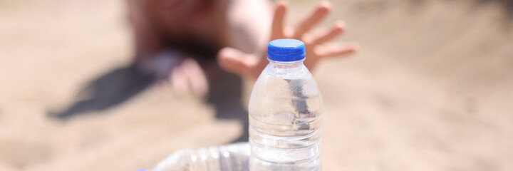 Male hands reaching for plastic water bottle in desert closeup