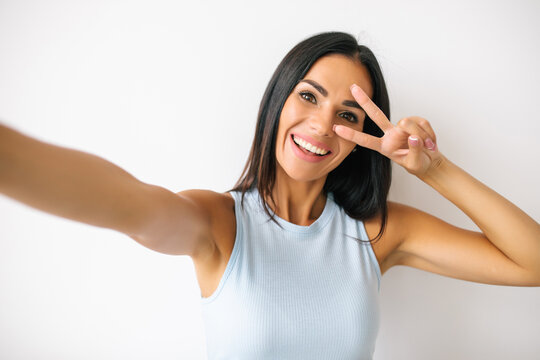 Portrait of a young attractive woman making selfie photo on smartphone on a white background