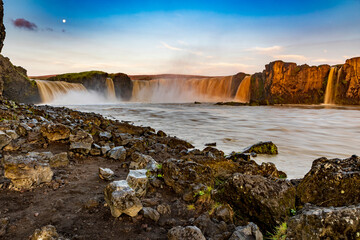 dramatic sky during sunrise illuminating the powerful Godifoss waterfall in Iceland.