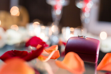 Gold ring, wedding ring in red box and, red heart on white-red background with beautiful bokeh. The moment of a wedding, anniversary, engagement, or Valentine's Day. Happy day.