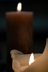 Two candles are glowing in a dark room 