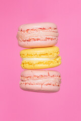 three macarons in the air on a pink background