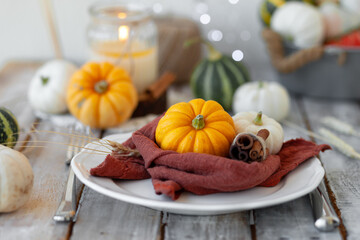Autumn table setting with pumpkins and candles. Zero waste concept, natural elemets. Fall home decoration for festive Thanksgiving family dinner. Wooden table.