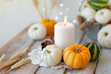 Obraz na płótnie Canvas Pumpkins and candle with fairy lights around on a wooden table. Autumn season image, cozy home atmosphere. Close up