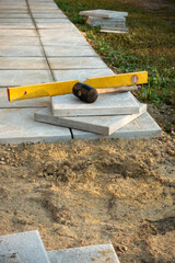 Laying a paving stone or brick. Gray concrete slabs in house courtyard on sand foundation base.