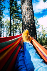 Legs point of view of outdoor leisure activity and relax on colorful hammock in the woods forest...
