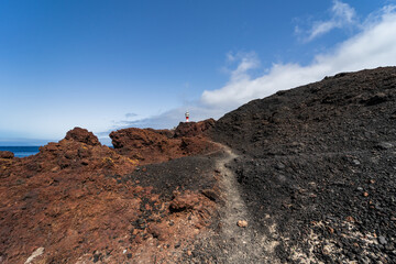 Rocky coast of the Atlantic Ocean at Cape Teno. A lighthouse in the background. Tenerife. Canary Islands. Spain.