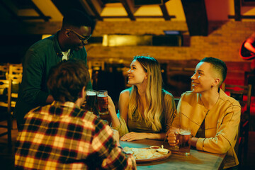 Group of young happy people toast during their night out in bar.