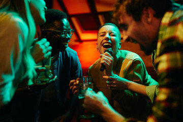 African American woman sings karaoke while spending the night out with her friends in pub. - obrazy, fototapety, plakaty