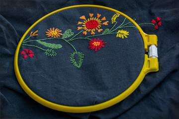 Hand embroidery in a hoop, pattern on dark fabric. Close-up. The concept of needlework, hobbies, leisure.