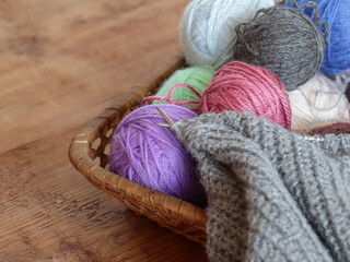 Fototapeta na wymiar Close up knitting yarn and fabric in progress in backet on wooden bckgroun
