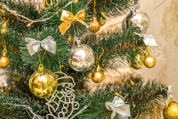 Christmas composition, gold and silver baubles, bows, animals, bells, lit garlands on a festive xmas fir tree against the decorative brick wall background. Copy-space. Winter holidays concept