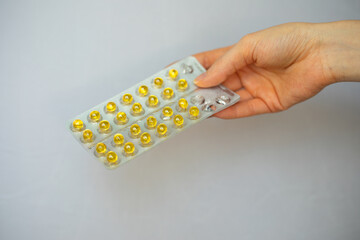 Yellow small round complex of vitamins and minerals in a blister pack in hand. Focus on the pills