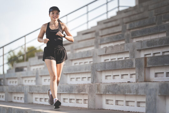 Healthy Adult Asian Female Running Up On Concrete Stairs Of The City Stadium