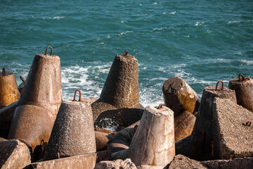 Strengthening the shore from erosion. Seashore with concrete blocks. The element of water. Waves break on concrete.