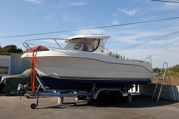 White boat with a motor on a car trailer