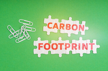 On a green background, paper clips and white puzzles with the inscription -Carbon offset