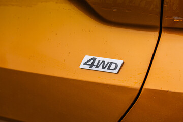 AWD emblem on modern orange SUV car detail close up view. All Wheel Drive chrome badge.