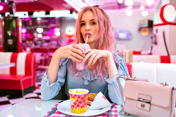 Positive lifestyle portrait of happy exited pretty woman with pink hairs having dinner
