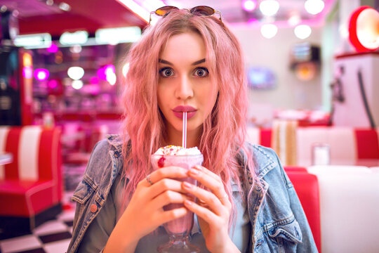 Positive lifestyle portrait of happy exited pretty woman with pink hairs having dinner