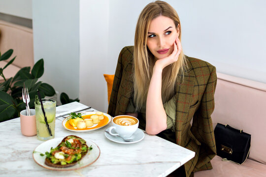 Young blonde pretty smiling woman enjoying tasty healthy brunch