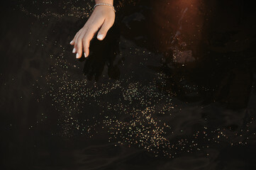 Fototapeta na wymiar female hand with sparkling glitters in sea