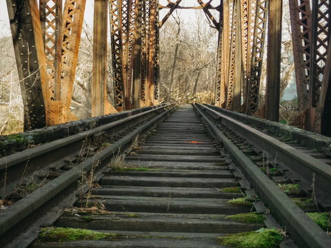 Railroad tracks running underneath brown metal bridge