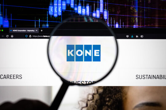 Kone company logo on a website with blurry stock market developments in the background, seen on a computer screen through a magnifying glass	