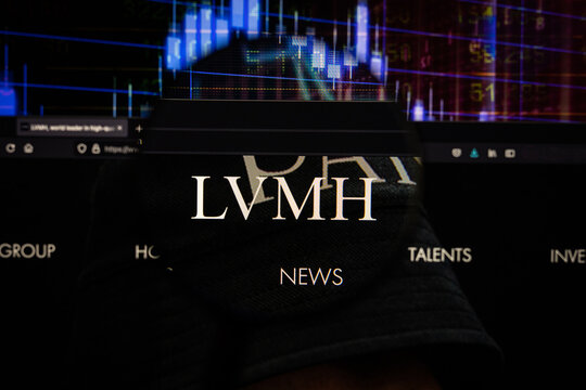 LVMH company logo on a website with blurry stock market developments in the background, seen on a computer screen through a magnifying glass	