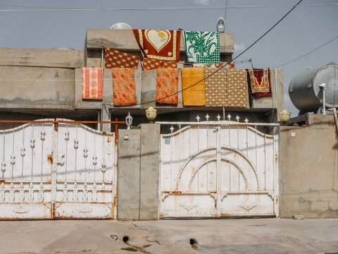 Colorful rugs hanging to dry above cinderblock wall with white metal doors