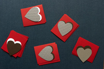 hand cut paper hearts on piles of paper squares on a dark background