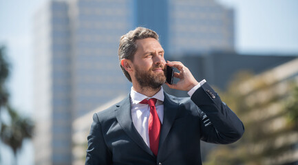 successful businessman in suit speaking on phone standing outdoor, communication