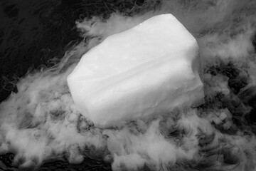 Dry ice evaporates in the water. Steam from a large piece of ice. Chemical experiment. - obrazy, fototapety, plakaty