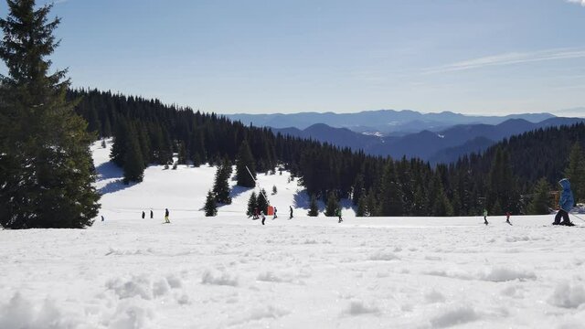 Skiers skiing downhill in mountain. 4K Wide Down Angle Static Shot. Pamporovo mountain winter resort, Snezhanka Peak, Bulgaria
