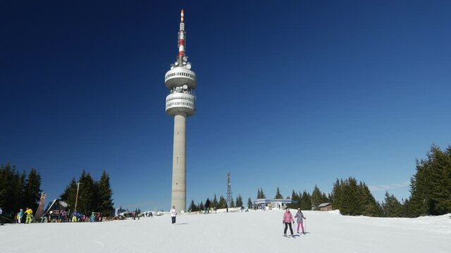 View of Snezhanka Peak with skiers and Tv tower on background. Pamporovo winter ski resort town, Rhodope Mountains, Bulgaria. 4K Wide Up Angle Static shot
