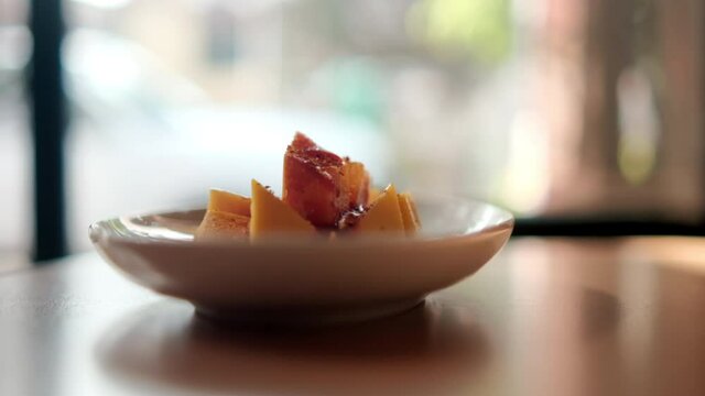 Plate of chopped mango with Mexican chamoy sauce and blurry background