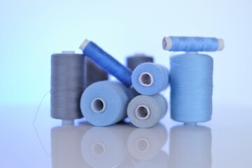  Sewing threads set.Blue and gray thread spools on a light blue background.Needlework and sewing...