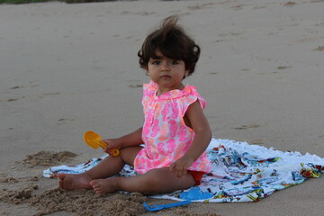 criança brincando na areia da praia com uma pazinha