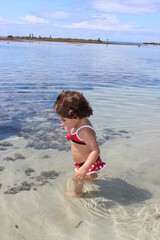 criança brincando na praia perto do mar